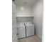 Bright laundry room featuring a washer and dryer, shelf, and white walls at 38150 W Bello Ln, Maricopa, AZ 85138