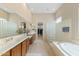 Bathroom featuring a dual vanity, a glass block wall, a soaking tub, and access to the walk-in closet at 42123 N Long Cove Way, Anthem, AZ 85086