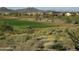 Wide view of the golf course, framed by desert foliage, showing houses nestled against the mountain backdrop at 42123 N Long Cove Way, Anthem, AZ 85086