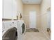 Functional laundry room with washer, dryer, storage cabinets, and tiled flooring, ready for everyday convenience at 42123 N Long Cove Way, Anthem, AZ 85086