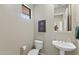 Well-lit powder room featuring a pedestal sink, toilet, decorative mirror, and modern fixtures at 42123 N Long Cove Way, Anthem, AZ 85086