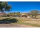 Community playground featuring a covered play structure, set among green grass, trees and offering a refreshing pool area in the background at 42256 W Lucera Ln, Maricopa, AZ 85138