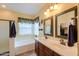 Elegant bathroom with double sinks, decorative mirrors, and a relaxing tub at 46175 W Morning View Ln, Maricopa, AZ 85139