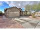 Single-story home featuring a two-car garage with a long driveway and desert landscaping at 46175 W Morning View Ln, Maricopa, AZ 85139