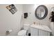 Stylish powder room with modern fixtures, round mirror, and unique wall art at 686 E Vermont Dr, Gilbert, AZ 85295