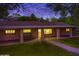 Stunning home exterior at dusk featuring a covered porch, well-kept lawn, and paved walkway at 7216 W Country Gables Dr, Peoria, AZ 85381