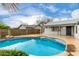 A clear blue pool is surrounded by desert landscaping, rock features and a grassy yard at 8027 E Quarterline Rd, Mesa, AZ 85207