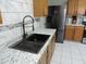 Close-up of a kitchen sink with modern fixtures, stainless steel refrigerator, and marbled granite countertops at 8163 E Posada Ave, Mesa, AZ 85212
