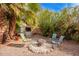 Cozy backyard fire pit area with gravel, bordered by mature trees and landscaping, creating a tranquil outdoor gathering space at 848 W Keating Ave, Mesa, AZ 85210