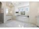 Bright bathroom with white marble flooring, built in tub, vanity, and decorative chandelier at 10050 N 58Th St, Paradise Valley, AZ 85253