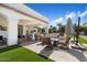 Outdoor kitchen and entertainment space featuring built-in BBQ, a seating area with an umbrella, and well-maintained synthetic grass at 10050 N 58Th St, Paradise Valley, AZ 85253