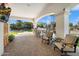 Covered outdoor patio area with seating, bar, and a TV overlooking the pristine pool and manicured grounds at 10050 N 58Th St, Paradise Valley, AZ 85253