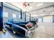 Showcases a spacious garage featuring car lifts, ample lighting, and a classic car with iconic tail fins at 10105 E Cactus Rd, Scottsdale, AZ 85260