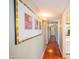 Hallway with wood floors and artwork leading to the bedrooms and bathrooms at 10105 E Cactus Rd, Scottsdale, AZ 85260
