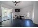 An open room with black floors, a ceiling fan, a refrigerator and a television on the wall at 10105 E Cactus Rd, Scottsdale, AZ 85260