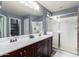 Bathroom featuring double sinks, dark wood cabinetry, and a glass-enclosed shower at 10156 E Radiant Ave, Mesa, AZ 85212
