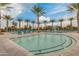 Beautiful community pool featuring inviting water, ample lounge chairs, and tall palm trees on a partly cloudy day at 10156 E Radiant Ave, Mesa, AZ 85212