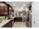 Bright kitchen with stainless steel appliances, dark wood cabinets, mosaic tile backsplash, and stone flooring at 10156 E Radiant Ave, Mesa, AZ 85212