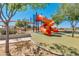 Community playground area featuring an orange twisty slide, climbing net and leafy trees at 10156 E Radiant Ave, Mesa, AZ 85212
