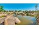 Scenic community pond with natural rock features and lush surrounding vegetation at 10156 E Radiant Ave, Mesa, AZ 85212
