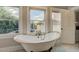 Bathroom featuring a clawfoot tub beneath windows, next to an open door and storage at 102 W Almeria Rd, Phoenix, AZ 85003