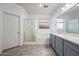 Well-lit bathroom featuring a double vanity, large mirror, and a glass-enclosed shower and tub combo at 10772 W Woodland Ave, Avondale, AZ 85323