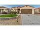 This home features a two-car garage, desert landscaping, and a well-manicured lawn at 10772 W Woodland Ave, Avondale, AZ 85323