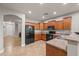 Kitchen features wood cabinets, black appliances, and view to the dining room at 10772 W Woodland Ave, Avondale, AZ 85323