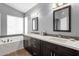 Stylish bathroom featuring a double vanity with quartz countertops, modern lighting, and a soaking tub at 12125 N 91St Way, Scottsdale, AZ 85260