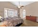 Comfortable main bedroom with a ceiling fan, bay windows, and doorway to a full bathroom at 12125 N 91St Way, Scottsdale, AZ 85260