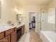 Bathroom featuring a dual sink vanity, a walk-in closet, and a separate shower and tub at 12508 W Highland Ave, Litchfield Park, AZ 85340
