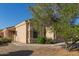 Tan desert home with xeriscaping, sidewalk leading to the front door, and a flowering tree at 12720 W Mandalay Ln, El Mirage, AZ 85335