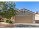 Beige home with a two-car garage and xeriscaped yard featuring an elegant flowering tree at 12720 W Mandalay Ln, El Mirage, AZ 85335