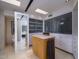 Modern walk-in closet features an island with marble countertop, frosted glass closet doors, and a full-length mirror at 1340 E Las Palmaritas Dr, Phoenix, AZ 85020