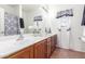 Bright bathroom with double sinks, a large mirror, and a shower with a black and white patterned curtain at 14363 W Acapulco Ln, Surprise, AZ 85379