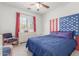 Comfortable bedroom with a large window, ceiling fan, and red, white, and blue decor at 14363 W Acapulco Ln, Surprise, AZ 85379
