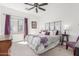 Bedroom with a floral comforter, decorative headboard, side tables, and a window with purple curtains at 14363 W Acapulco Ln, Surprise, AZ 85379