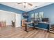 A home office with blue walls, wood floors, a work station, and a window view at 14363 W Acapulco Ln, Surprise, AZ 85379