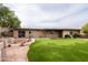 A view of the brick home's exterior and the backyard with artificial turf and desert landscaping at 14625 N 25Th Pl, Phoenix, AZ 85032