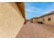 View of the gravel lined backyard with a peek at the neighboring houses with a vibrant blue sky above at 15046 W Cooperstown Way, Surprise, AZ 85374