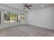 Spacious bedroom with neutral carpet, ceiling fan, and view of the front yard at 15046 W Cooperstown Way, Surprise, AZ 85374