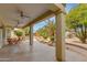 A covered patio with ceiling fans overlooks the thoughtfully landscaped backyard at 15046 W Cooperstown Way, Surprise, AZ 85374