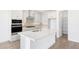 Modern white kitchen featuring stainless steel appliances, a spacious island with a sink, and ample cabinet space at 17264 W Via Dona Rd, Surprise, AZ 85387