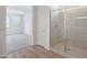 Modern bathroom featuring a glass shower with tile surround, wood look floor, and an open view to the bedroom at 17295 W Via Dona Rd, Surprise, AZ 85387