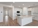 Bright, open-concept kitchen showcasing white cabinetry, stainless steel appliances, and an island with quartz countertops at 17295 W Via Dona Rd, Surprise, AZ 85387
