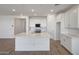 Bright, open-concept kitchen showcasing white cabinetry, stainless steel appliances, and an island with quartz countertops at 17295 W Via Dona Rd, Surprise, AZ 85387