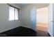 Bedroom with dark floors, natural light from the window, and an open door at 17633 W Wind Song Ave, Goodyear, AZ 85338