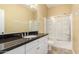 Bright bathroom featuring a black granite countertop, white cabinets, and a shower with glass doors at 19550 N Grayhawk Dr # 1044, Scottsdale, AZ 85255
