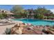 A lavish community pool is surrounded by lounge chairs, native landscaping, and desert fauna at 19550 N Grayhawk Dr # 1044, Scottsdale, AZ 85255