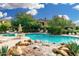 A refreshing community pool complete with a rock waterfall, desert plants, and mature trees at 19550 N Grayhawk Dr # 1044, Scottsdale, AZ 85255